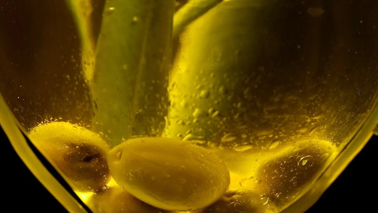 Close-up of golden olive oil with garlic cloves submerged, emphasizing color and texture for the cooking smoke-point discussion.