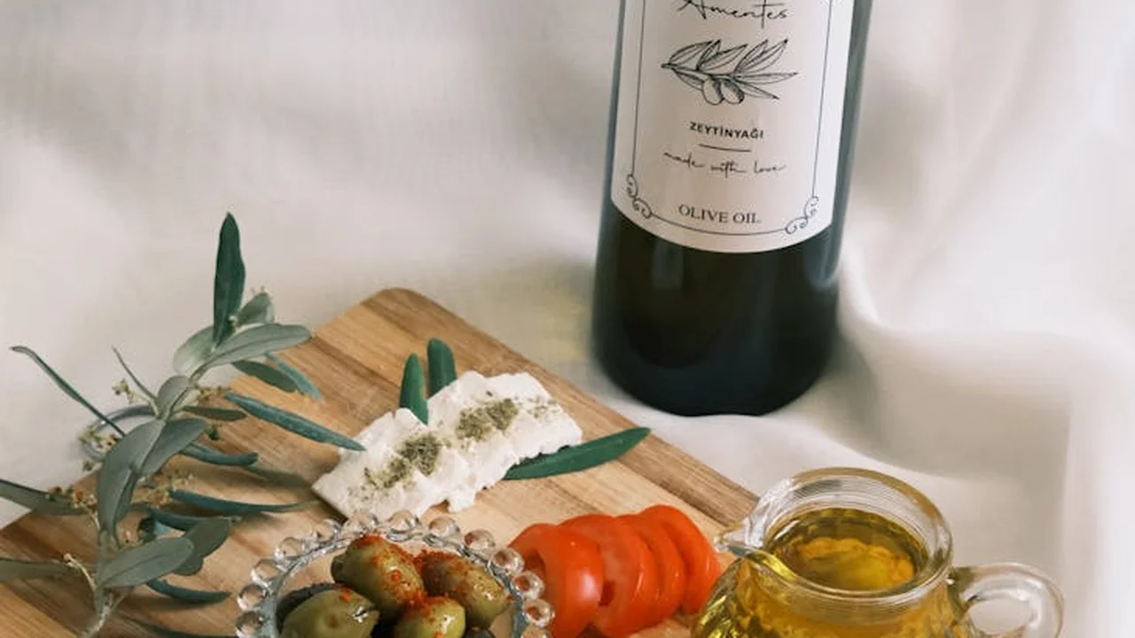 Olive oil bottle behind a cutting board with herbs, salt, and a small jar of oil.