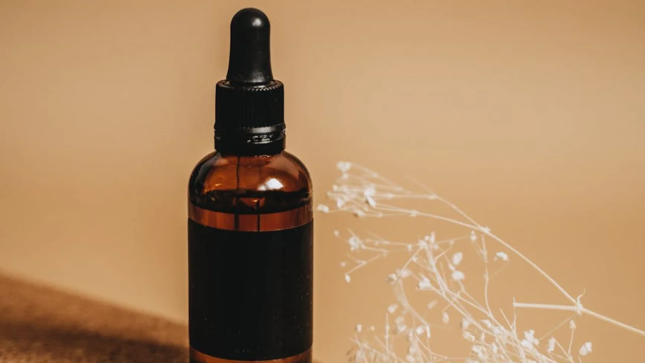 Brown glass dropper bottle of oregano oil on a wooden surface with a black label and dropper top
