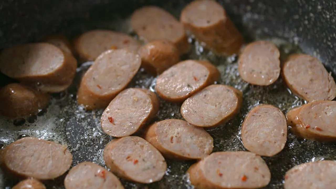 Sliced sausage pieces frying in hot oil in a skillet