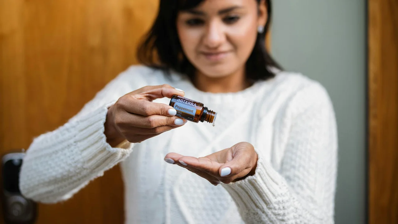 Person holding a small amber bottle and dispensing essential oil onto their open palm