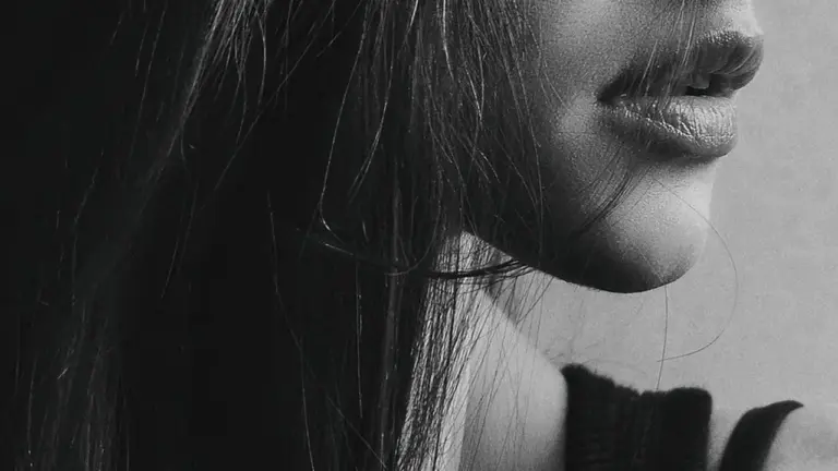 Close-up grayscale side-profile of a woman's face, focusing on lips and jawline with hair partially covering.