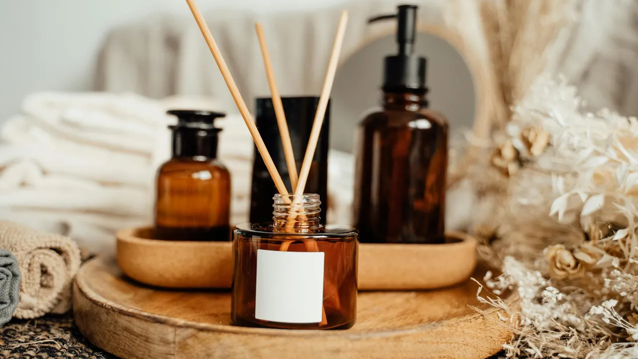 Amber glass bottles with dried herbs and a wooden tray, ready for olive and herb infused oil preparation in a cozy home setting