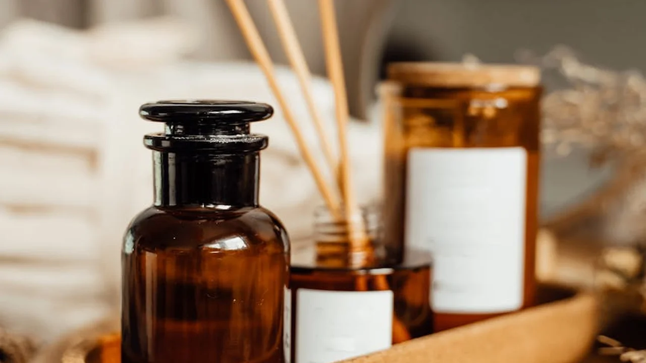 Amber glass bottles and jars with a wooden tray and diffusers, arranged for lavender and peppermint infusion preparation.