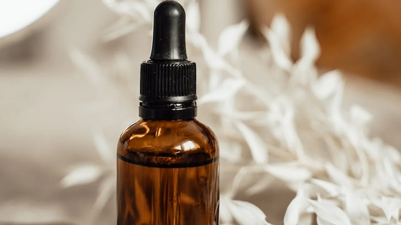 Amber glass bottle with dropper containing rosehip oil on a soft, neutral background