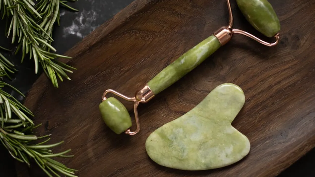 Fresh rosemary sprigs on a wooden surface with a jade roller.