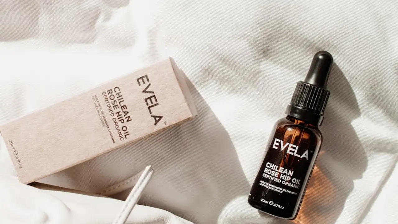 EVELA Chilean Rose Hip Oil bottle and its box resting on a white textured fabric surface.