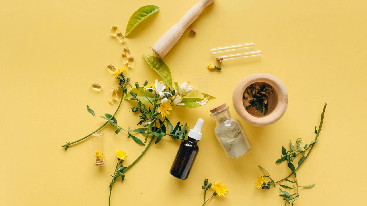 Assorted herbs, essential oil dropper, mortar and pestle on a yellow background, suggesting natural ingredients and kitchen tools for smoke-free cooking