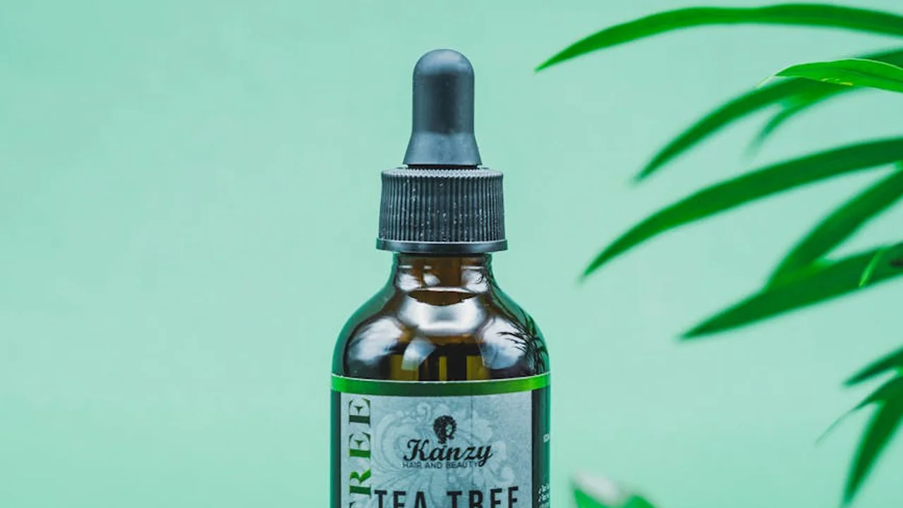 Dropper bottle of tea tree oil with green background and plant leaves