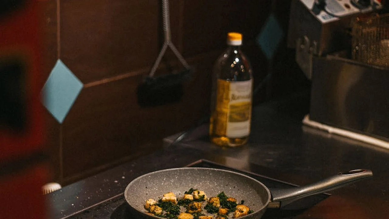 A nonstick skillet on a stove with a bottle of vegetable oil in the background, illustrating substitution in cooking.