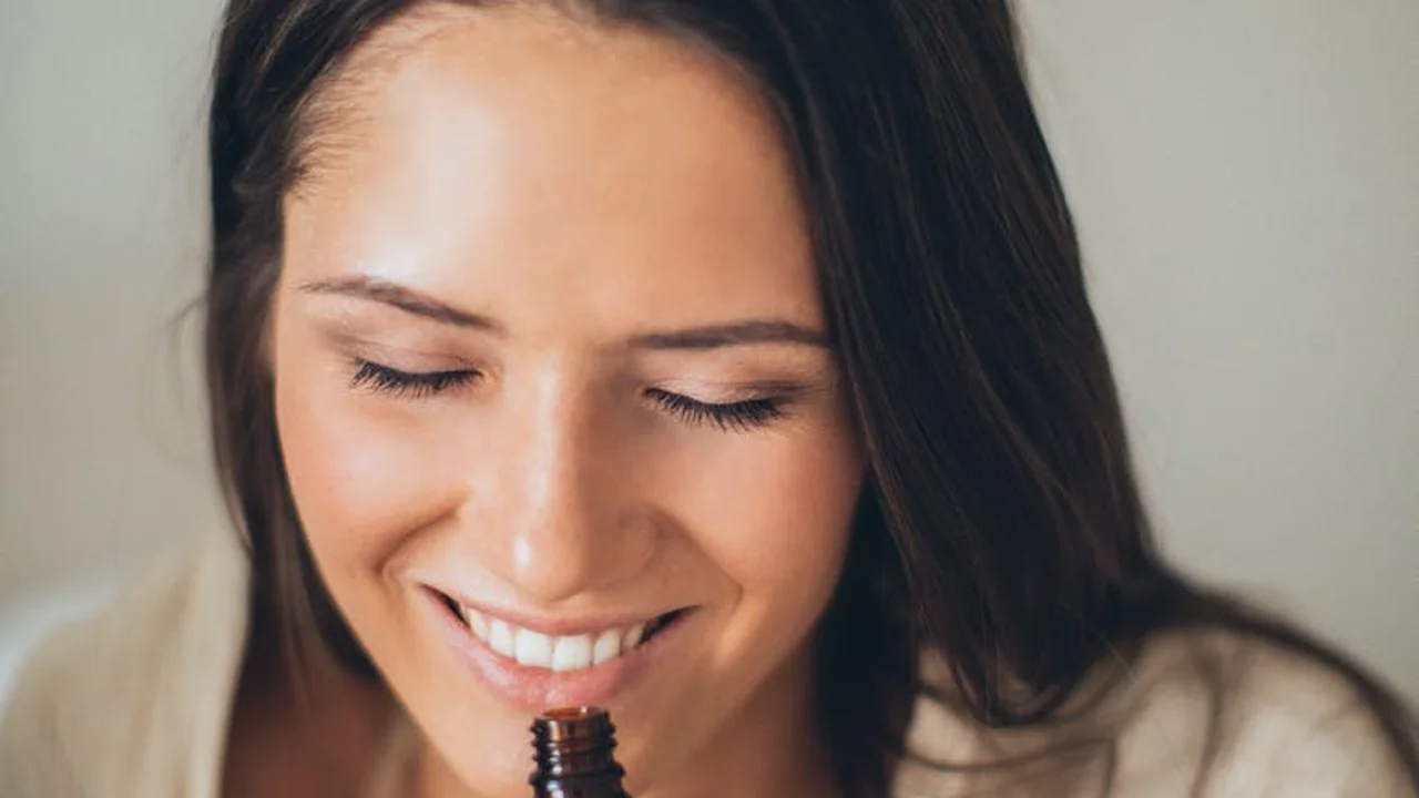 Smiling woman sniffing a small bottle of oil
