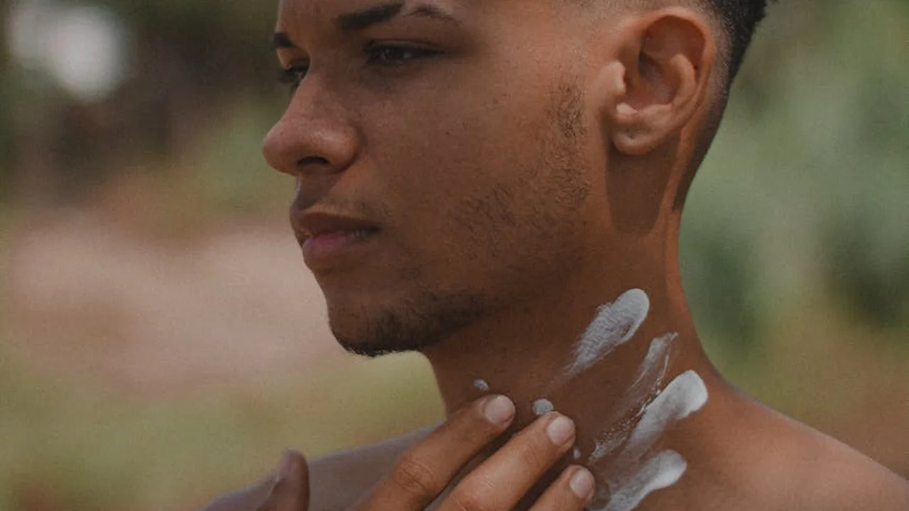 Close-up of a person with a small amount of white cream on their neck and fingertips as they prepare skincare.